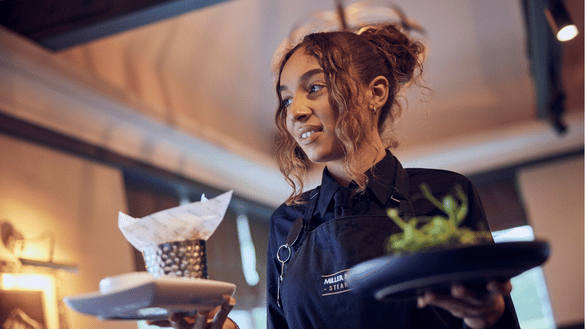 A member of waiting team in a Miller & Carter takes food to a table